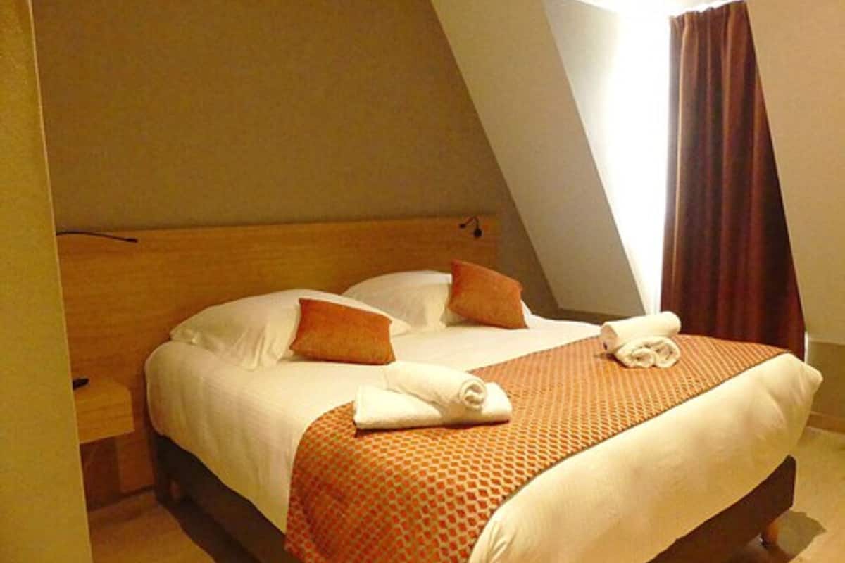 Quarto de hotel com cama, almofadas e manta.