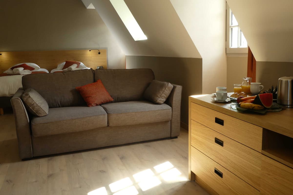 Quarto moderno com sofá, cómoda de madeira e espaço para refeições.