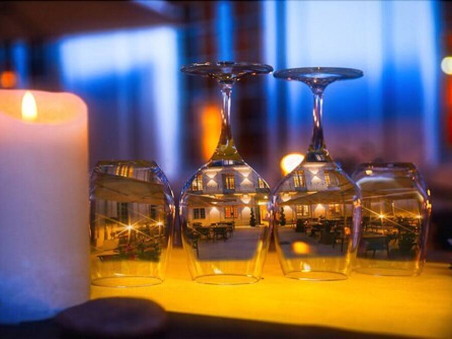 Velas y cuatro copas de vino sobre una mesa con un brillo cálido.