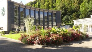 Een modern gebouw met grote ramen en een tuin vol planten en bloemen erbij.