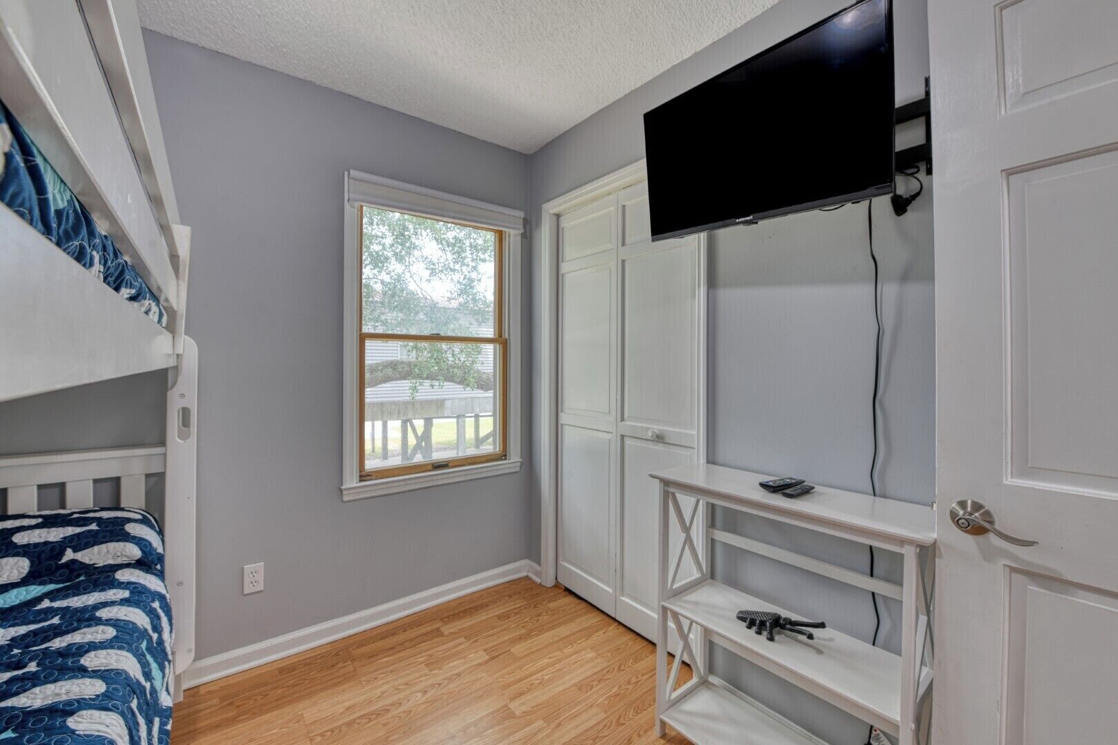 A bedroom with bunk beds, a TV, a window, and a white door.