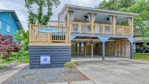 Ein Holzhaus mit Balkon und überdachtem Bereich, mit der Aufschrift "ONANA" und "VERMIETUNG" für Garden City Realty.