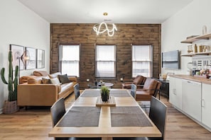 A modern living room with a wooden wall, a dining table, and a kitchen area. - Top-Rated 1BR Near Convention Center & Stadiums (Covington)