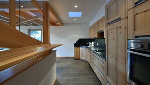 A modern kitchen with wooden cabinets, a skylight, and a built-in oven.
