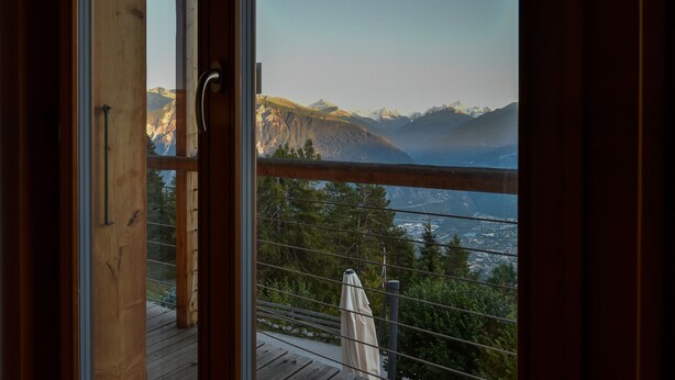 A wooden deck with a view of mountains and a lake.
