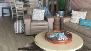 A living room with a sofa, a coffee table, and a dining area with chairs and a table. - Beach Paradise Found!  Direct oceanfront 9th floor updated and nicely decorated (Jensen Beach)