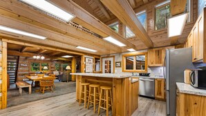 L’intérieur d’une cabane en bois comprend une cuisine, un coin repas et des tabourets de bar.