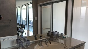A modern bathroom with a large sink, a mirror, and a glass dispenser. - Villa Ocean Kamaguchi (Awaji)