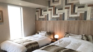 A hotel room with two beds, a wooden headboard, a wall with a geometric pattern, and a bedside lamp. - Villa Ocean Kamaguchi (Awaji)