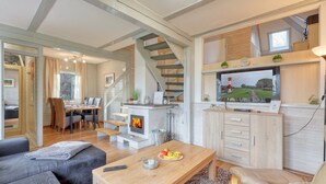 A cozy living room with a fireplace, a dining area, and a staircase leading to an upper level.