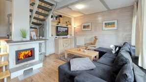 A modern living room with a fireplace, a sofa, a coffee table, and a staircase leading to an upper level.