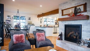 A modern living room with a fireplace, dining area, and kitchen in the background. - Mabel and Harry's, a modern country guest house (Kokomo)