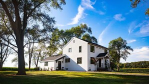 A two-story white house with a front porch, surrounded by trees and a well-maintained lawn. - Mabel and Harry's, a modern country guest house (Kokomo)