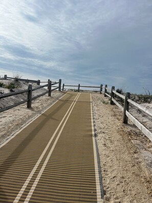 A sandy beach path with a textured mat and wooden railings. - Beach Block! Beach Tags, Central AC, Grill and Patio! (Seaside Park)