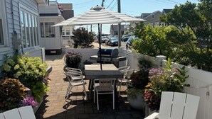Eine Terrasse mit Grill, Gartenmöbeln und Blick auf die Nachbarschaft.