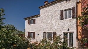 Un bâtiment à deux étages doté d’une façade à motifs, de nombreuses fenêtres avec volets et d’une porte bien visible.