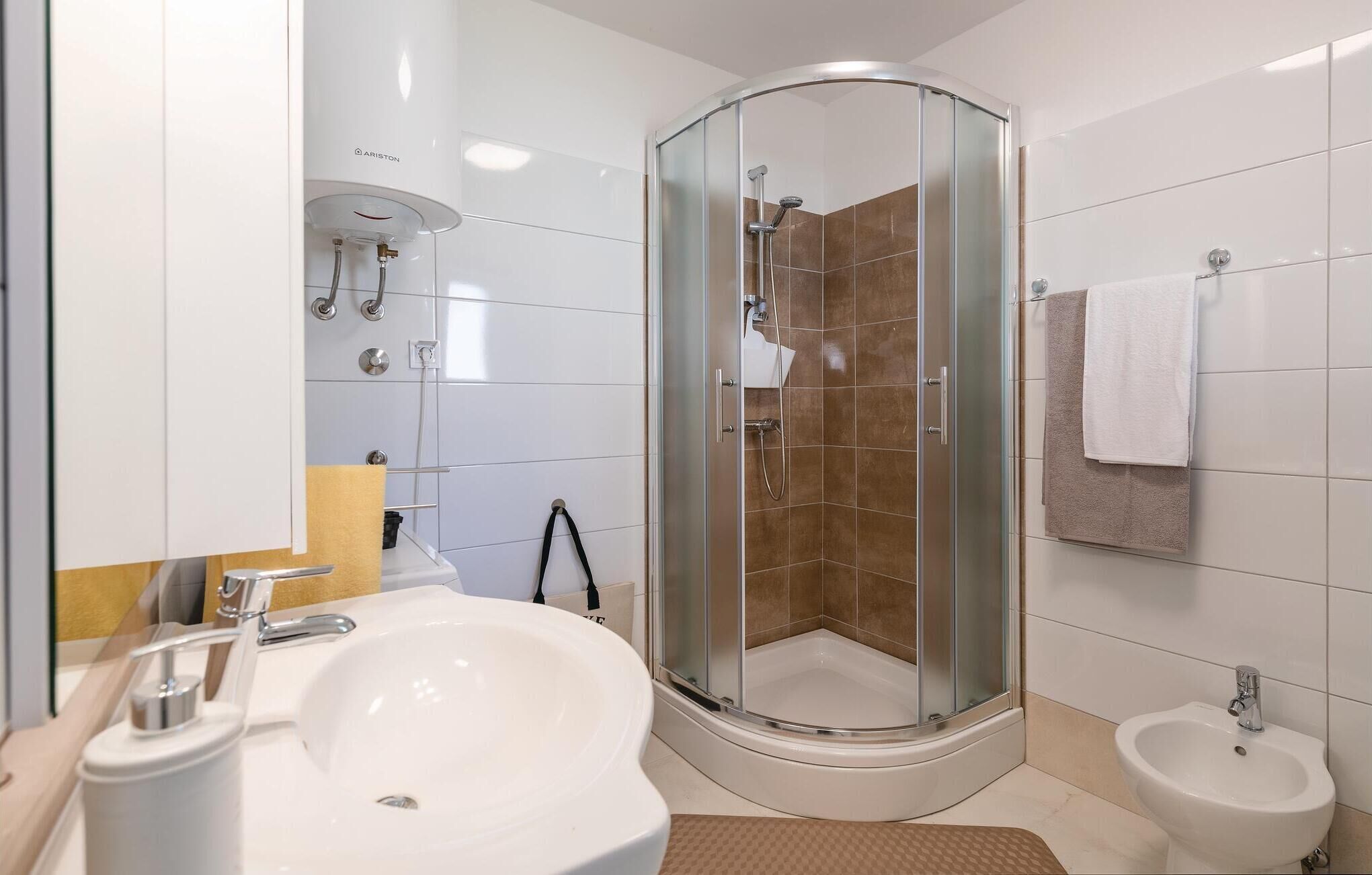 Une salle de bain moderne avec une douche à parois de verre, un lavabo et un bidet.
