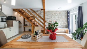 Une cuisine moderne avec des poutres en bois, un mur en pierre et un coin repas comprenant une table et des chaises en bois.