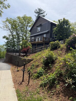 A two-story house with a balcony, surrounded by trees and shrubs.