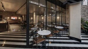 Ett modernt café med svart- och vitrutigt golv, glasväggar och en tegelvägg.