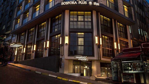 Ett hotell med flera våningar, en böjd fasad, upplysta fönster och en tydlig entré med skyltar.