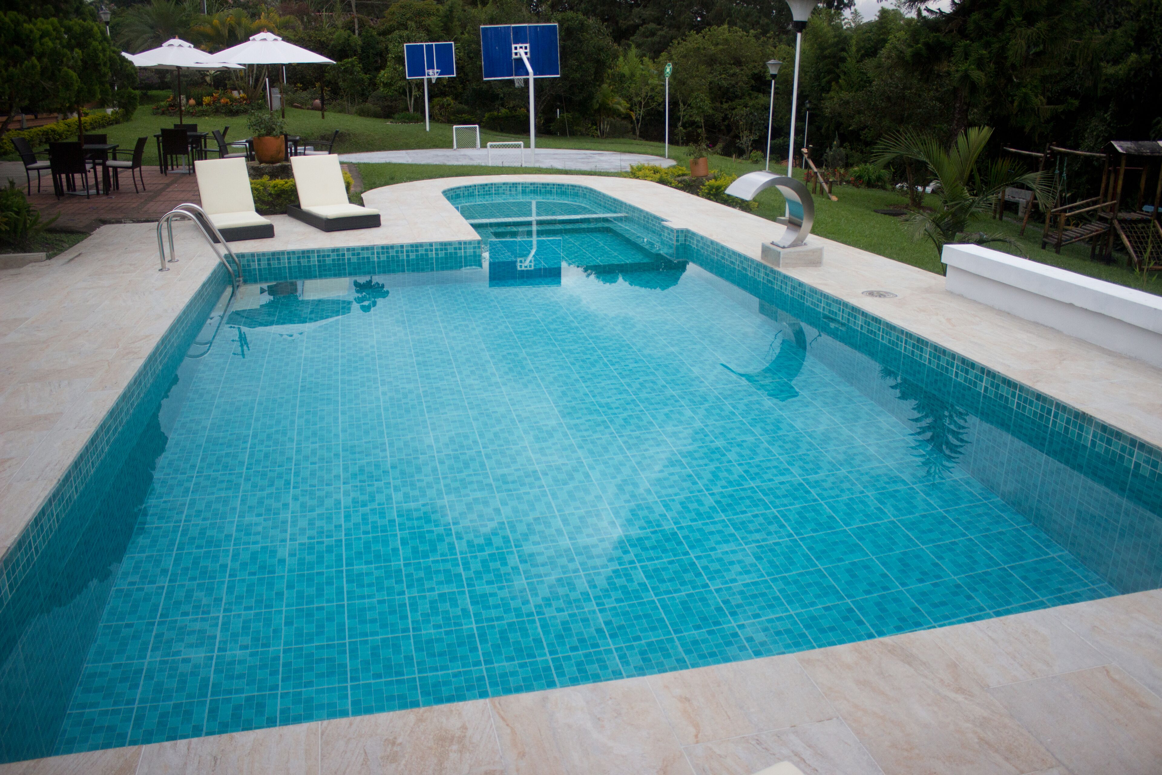 Una piscina al aire libre, sombrillas, sillones reclinables de piscina