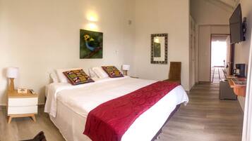 A hotel room with a bed, a nightstand, a lamp, a painting, a mirror, and a TV.
