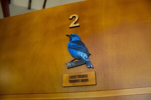 Una mesa de madera con el número 2 y una placa con forma de pájaro.