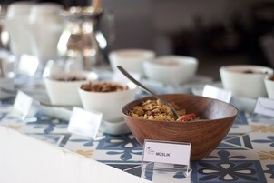 A breakfast buffet with various bowls of food, including a bowl labeled "MÜSLIK".