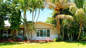 A house with a yellow exterior, surrounded by lush greenery and palm trees. - Melbourne-Indialantic-by-the-Sea, Florida (Indialantic)