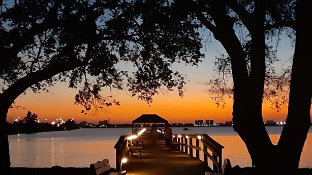 A wooden pier extending into calm water, surrounded by trees, with a building at the end. - Melbourne-Indialantic-by-the-Sea, Florida (Indialantic)