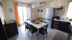 A compact kitchen with a dining table, chairs, a refrigerator, microwave, and a small countertop. - MODERN AND COZY APARTMENT NEAR THE SEA OF RECANATI (Giardini Naxos)