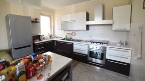 A modern kitchen with stainless steel appliances, black and white cabinetry, and a tiled backsplash. - MODERN AND COZY APARTMENT NEAR THE SEA OF RECANATI (Giardini Naxos)