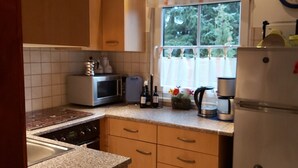 Una cocina con armarios de madera, microondas, cafetera y refrigerador.