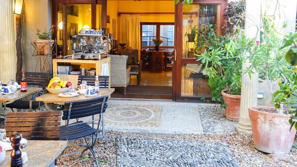 An outdoor dining area with tables and chairs, a grill, and potted plants. - Rosedene Lodge (Cape Town)