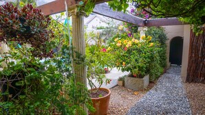 A garden with potted plants, a stone pathway, and a pergola structure. - Rosedene Lodge (Cape Town)