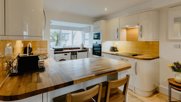 Eine moderne Küche mit weißen Schränken, einer Holz Arbeitsplatte und einem eingebauten Backofen.