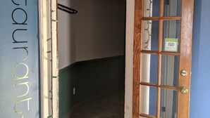 Um corredor com porta de madeira, uma placa indicando "restaurant bar" e chão de madeira.