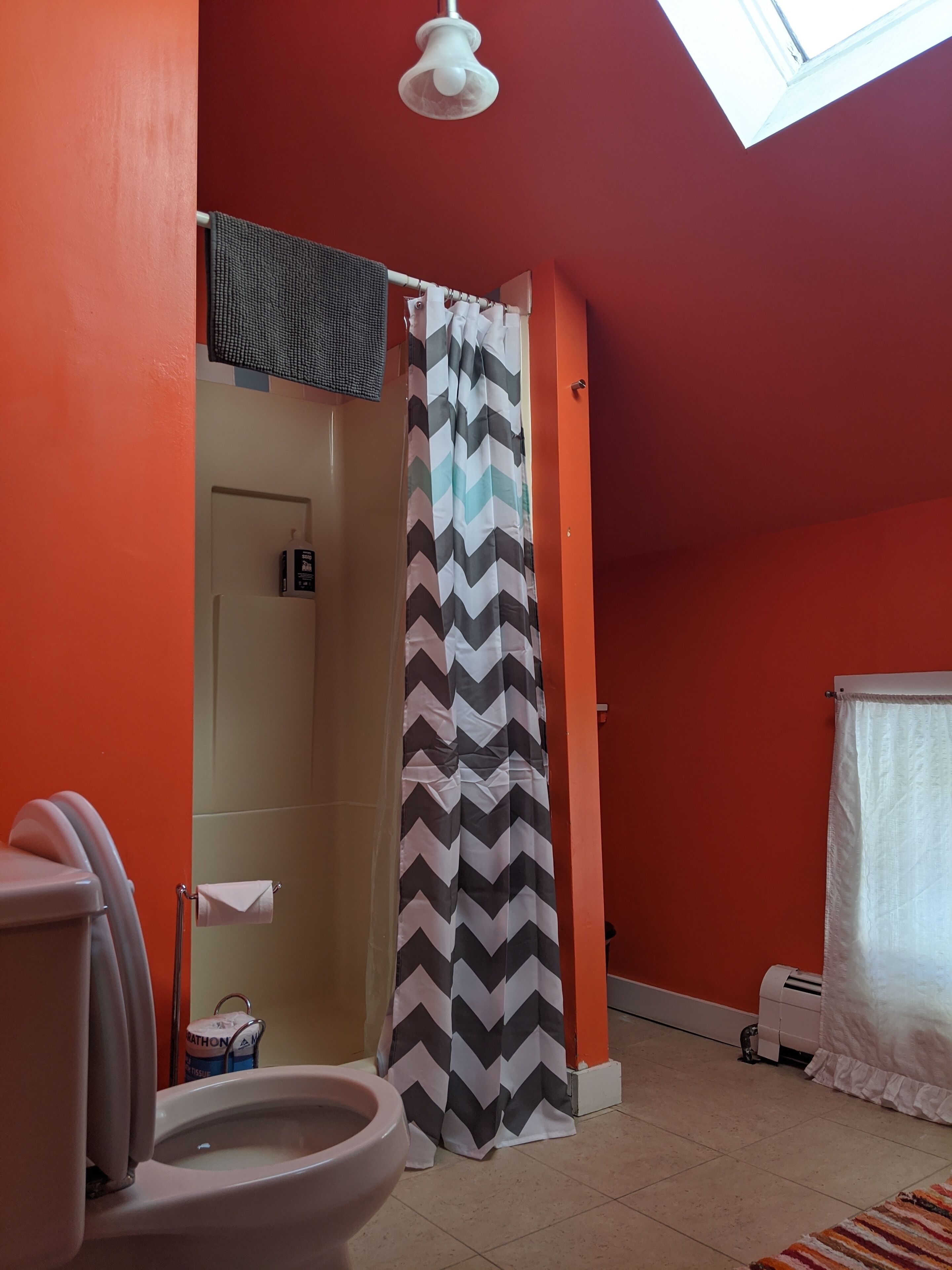 A bathroom with a toilet, a shower curtain, and a ceiling fan.