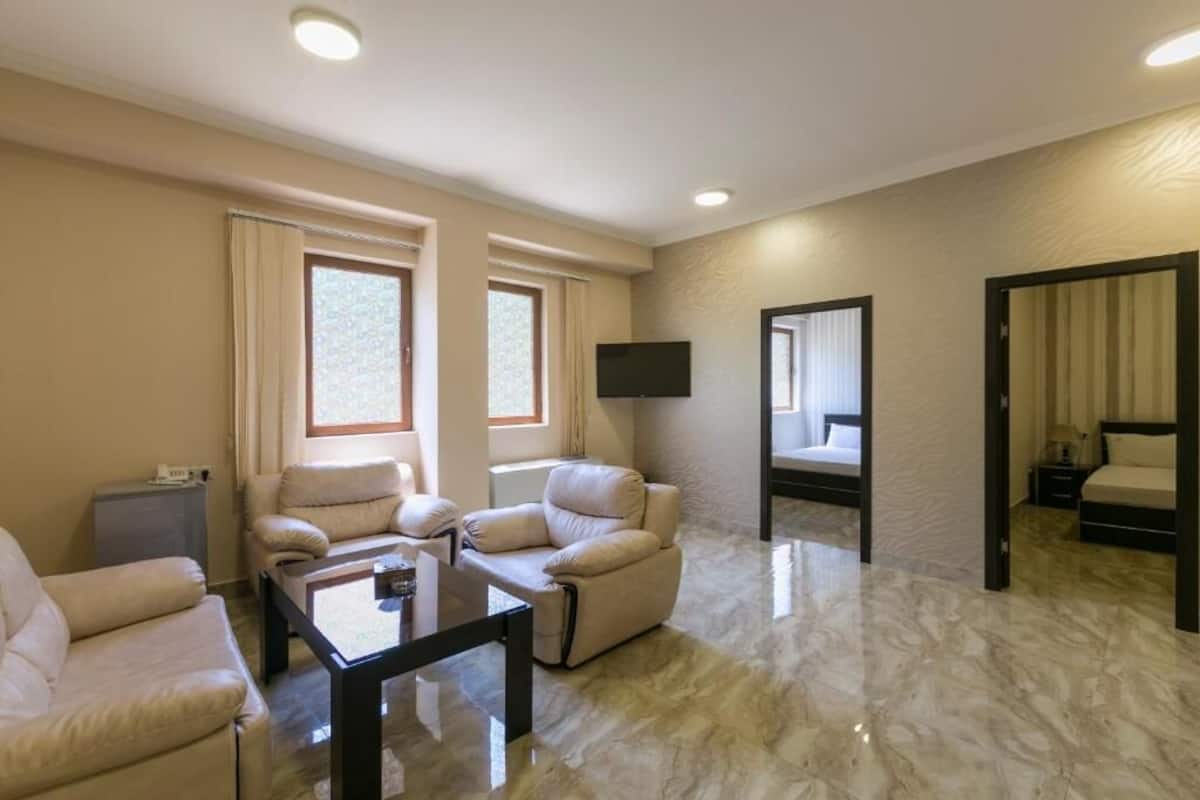 Deluxe Quadruple Room, 2 Queen Beds | Living area | 32-inch LCD TV with cable channels, TV