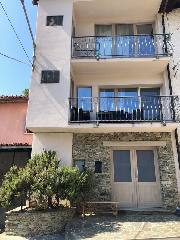A multi-story building with balconies, a stone facade, and a wooden door.