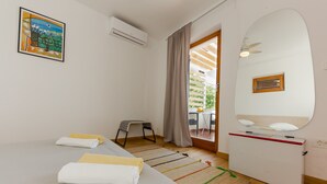 Une chambre à coucher avec un lit, un bureau, une chaise, une fenêtre avec des rideaux et un tableau au mur.