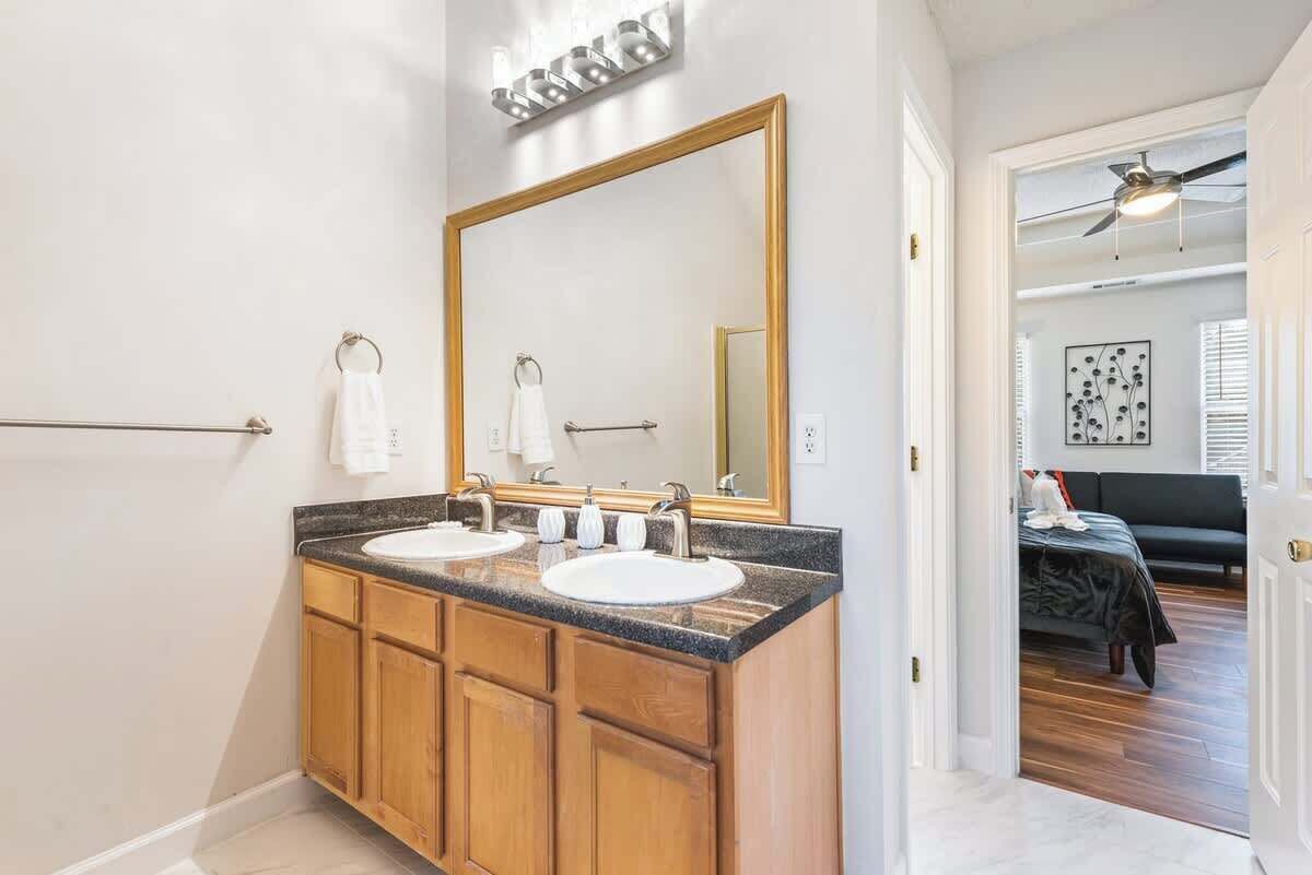 A bathroom with two sinks, a large mirror, and wooden cabinets.