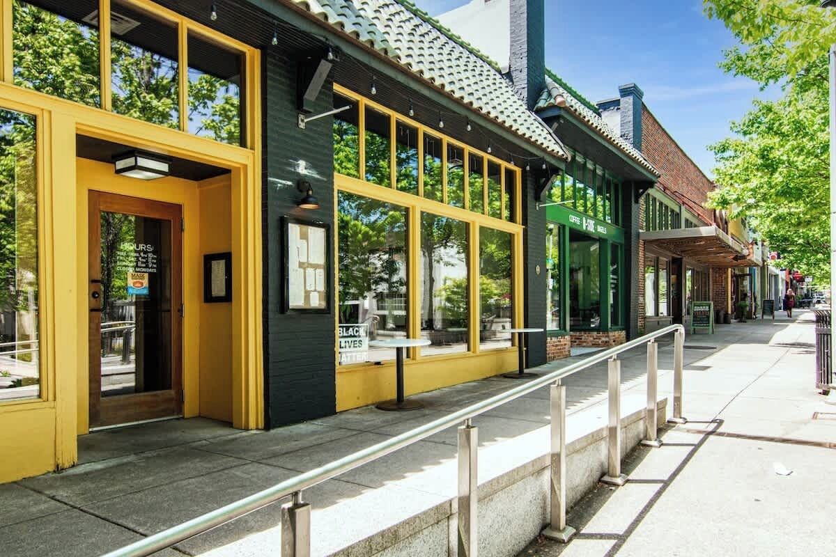 Un edificio con grandes ventanas, una puerta amarilla y un cartel que dice 'BLACK LIVES MATTER'.