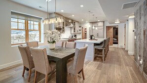 A modern kitchen with a central island, pendant lighting, and a large window.