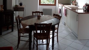 A kitchen with a dining table, chairs, cabinets, a window, and a radiator. - House, large balcony with stairs down to the garden. (L'Argentière-la-Bessée)