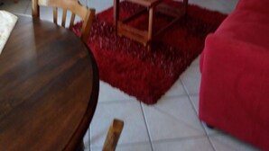 A living room with a wooden coffee table, a red sofa, a television, and a cabinet. - House, large balcony with stairs down to the garden. (L'Argentière-la-Bessée)
