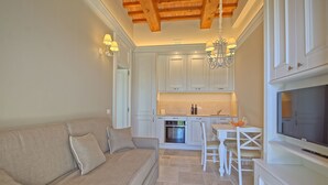 Una cucina compatta con mobili bianchi, un forno integrato e un'area pranzo con sedie bianche.
