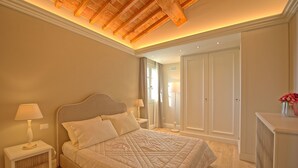 A bedroom with a large bed, bedside lamps, a radiator, and a wardrobe. - Sole di Vino 2 - Apartment with pool (Vinci)