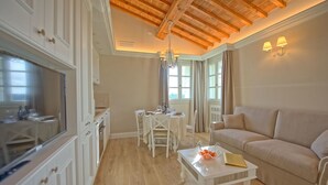 A spacious living area with a high wooden ceiling, a dining table set for four, and a beige sofa. - Sole di Vino 2 - Apartment with pool (Vinci)